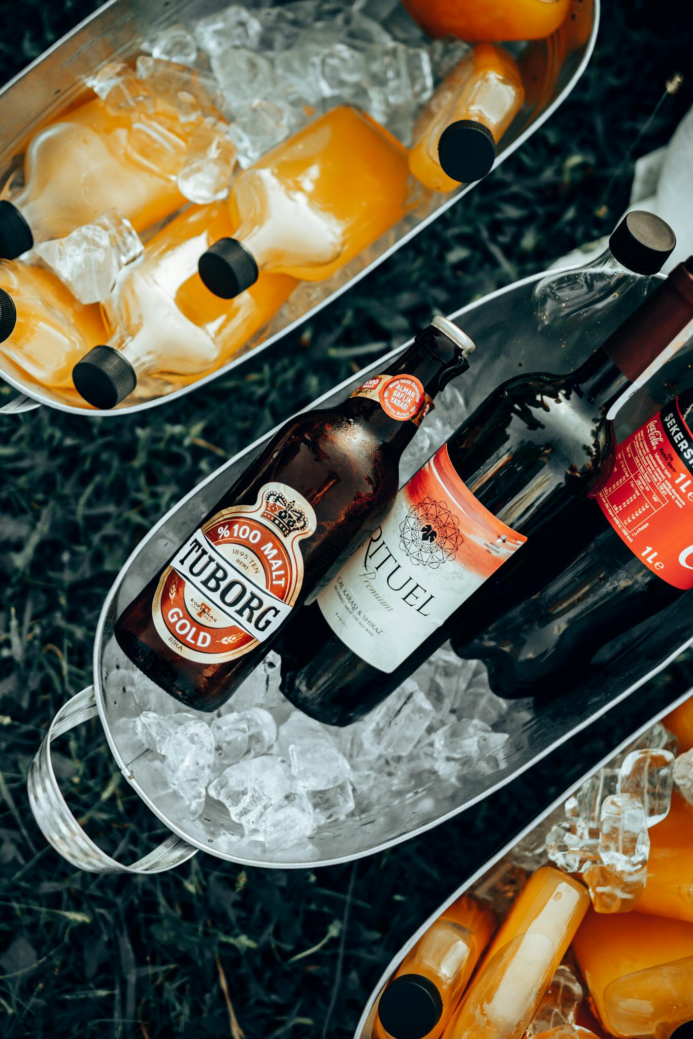 Overhead view of bottles of beer and juice chilling in ice buckets. Perfect for outdoor summer gatherings.